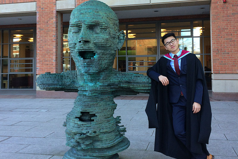 Rory Cao with the statue outside the McClay