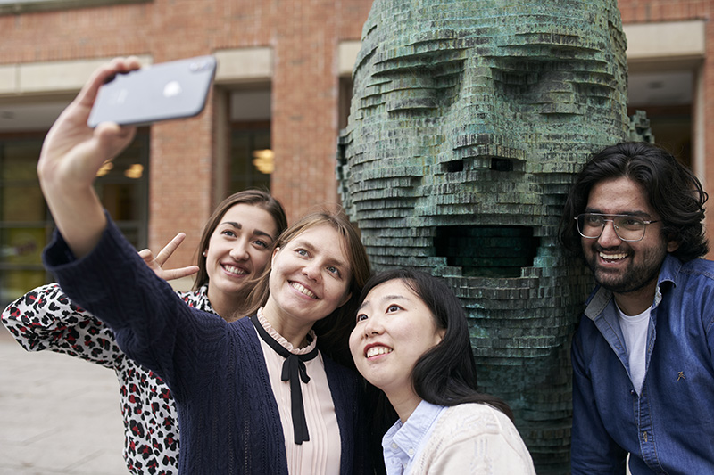 Yuan taking a selfie with friends outside the McClay library