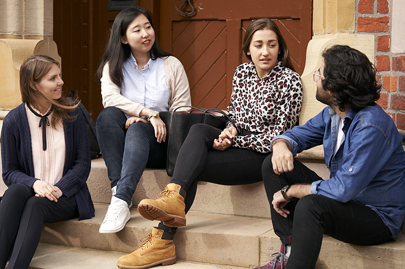 Yuan with friends sitting outside Queen's 800x533