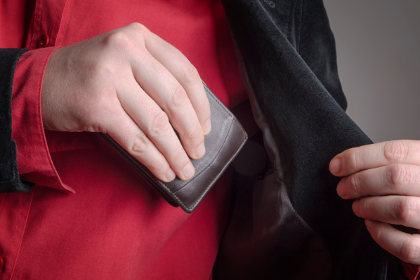 Image shows someone putting their wallet into their jacket pocket