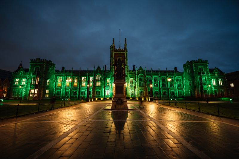 Front of the Lanyon Building light up in green against a dark night sky.