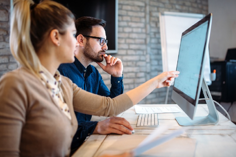 Man and Woman Sitting at Computer Screen