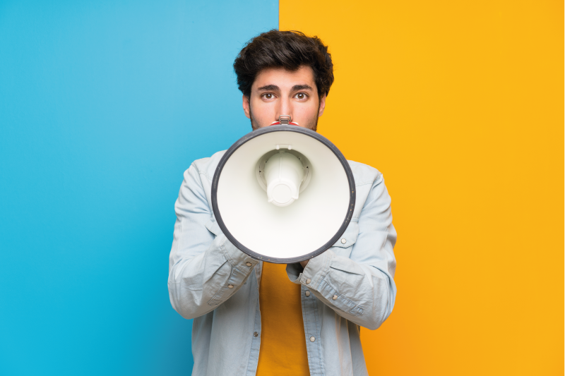 a student with a microphone standing in front of a background, half yellow, half blue