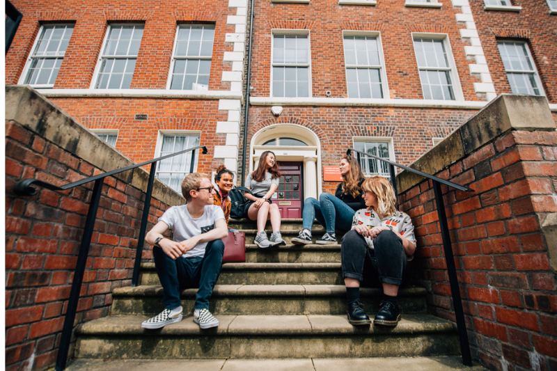 students sitting together on steps outside a building at Queen's University