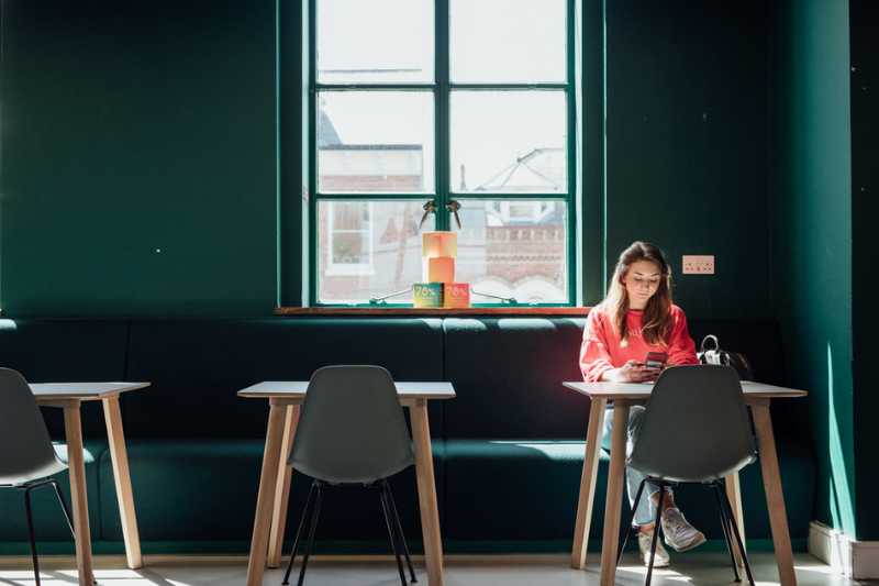 student sitting alone at a small table in a break out area in Queen's University