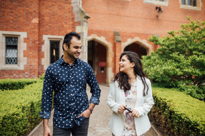 two international students, one male and one female walking in University grounds chatting