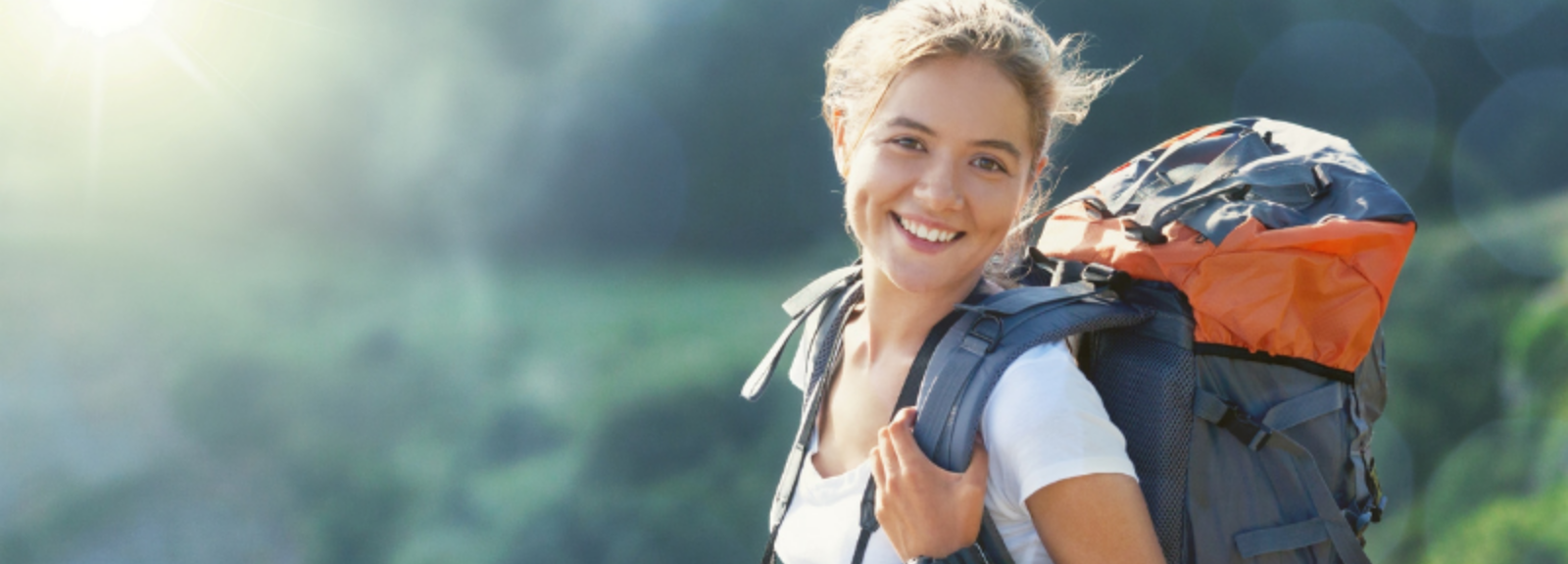 female backpacker smiling at camera from a mountain top