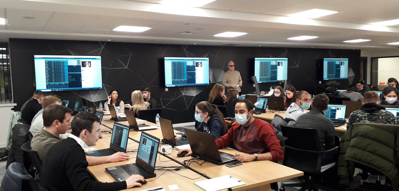 students sitting in the computer science building on laptops in Queen's University completing the Stock Market Challenge