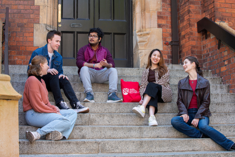 students sitting outside a building at Queen's University chatting