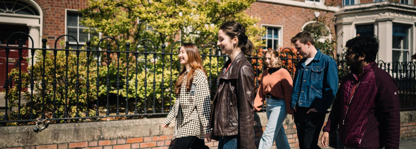 a group of students walking around queen's university campus