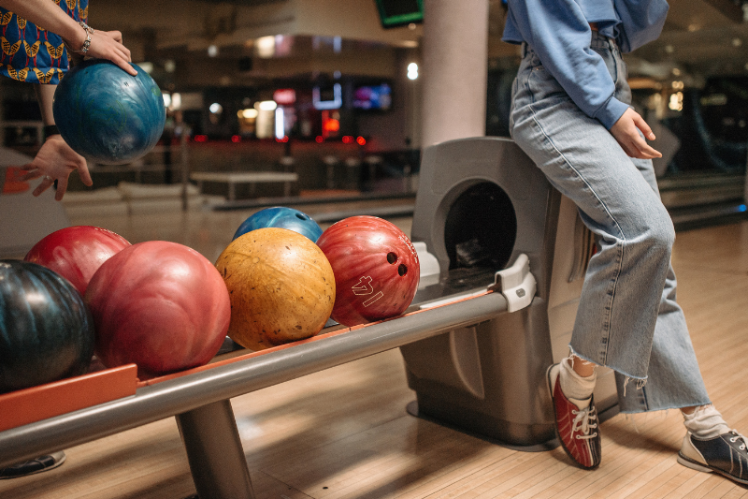 A student standing beside the rack of bowling balls, ready to pick one up.
