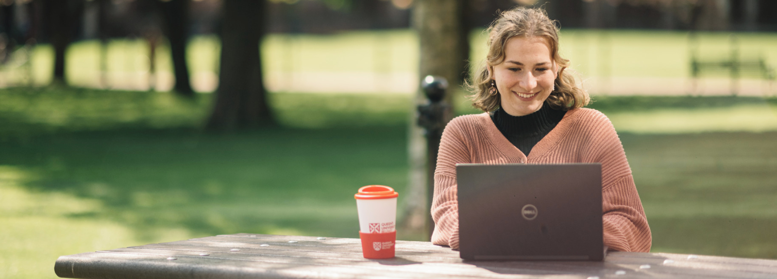 female student sitting at a laptop in Queen's University grounds