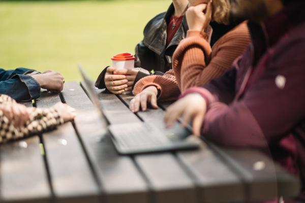 A student opening their laptop on the picnic benches in the Quad.