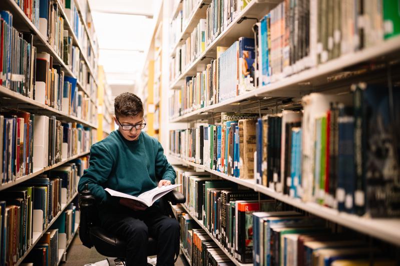 A student with a disability reading a book in the library