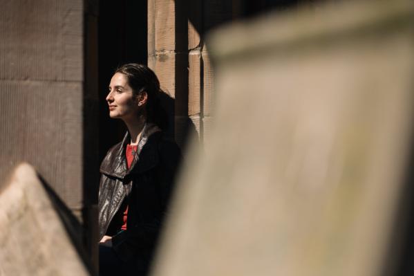 A student standing up against a wall in the Cloisters, QUB