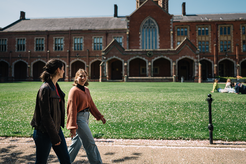 Two students walking through the quadrangle at Queen
