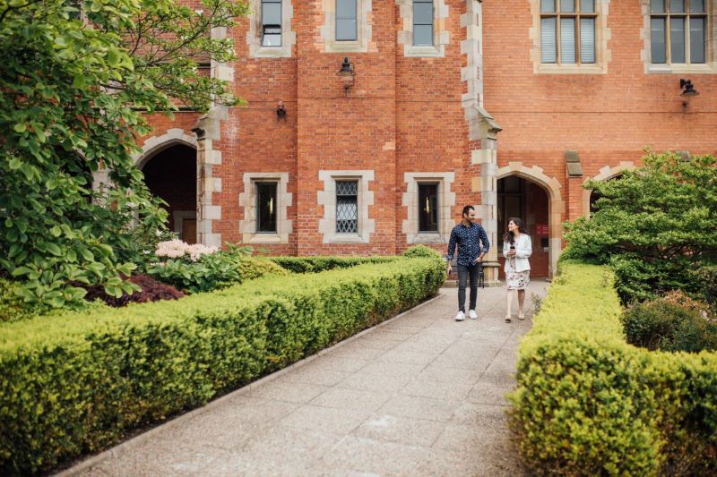 Man and woman chatting and walking in the Quad QUB