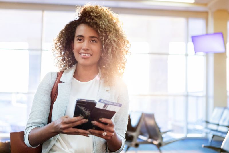 young woman in airport with boarding pass and phone