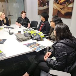 students sitting at an employer office around a big desk talking to an employer