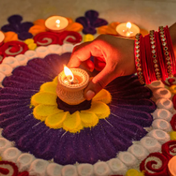 Image shows a person holding a candle celebrating Diwali