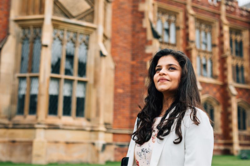 female student standing outside main entrance of Queen's University