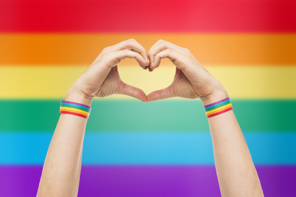 Image shows a pride flag and hands making a heart shape