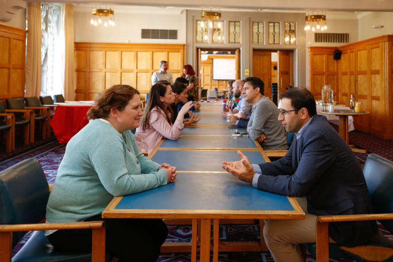 Image shows members of the Fellowship Academy conversing at a long table at a networking event in the Canada Room & Council Chamber