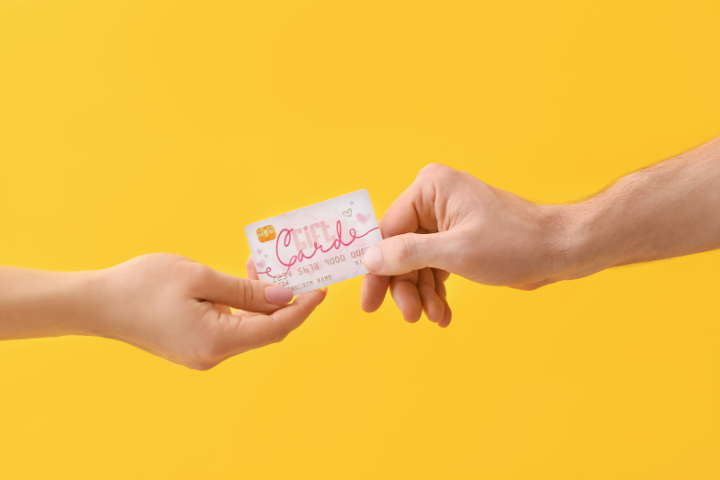 Image shows two hands passing a gift card between one another