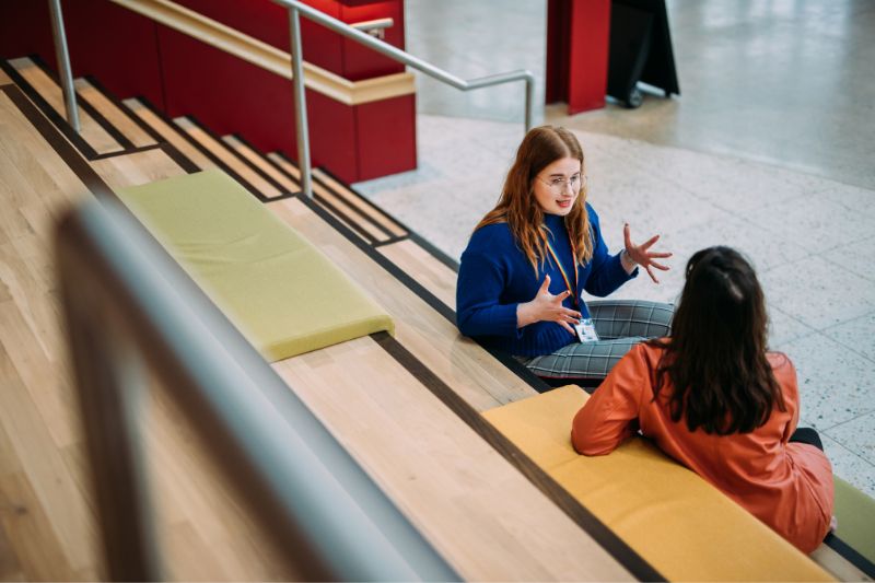 two females sitting chatting on staircase