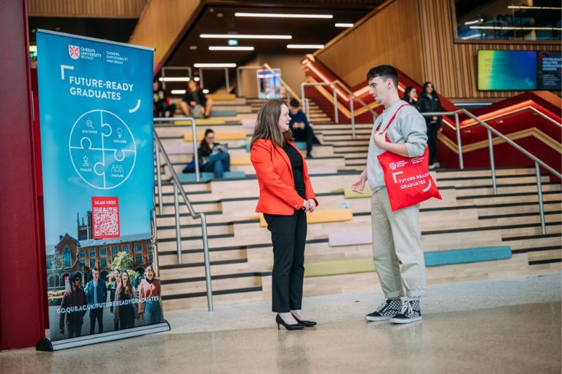 univeristy staff member standing talking to a student in lobby