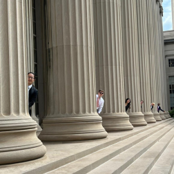 students standing behind pillars and peering out in Boston