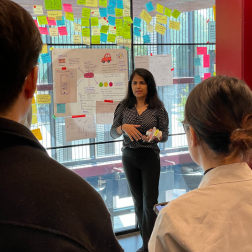 employer standing talking to some students whilst hanging up some post it notes