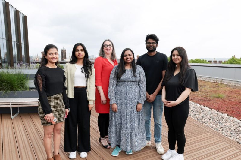 students standing on a roof terrace with a member of Queen's staff