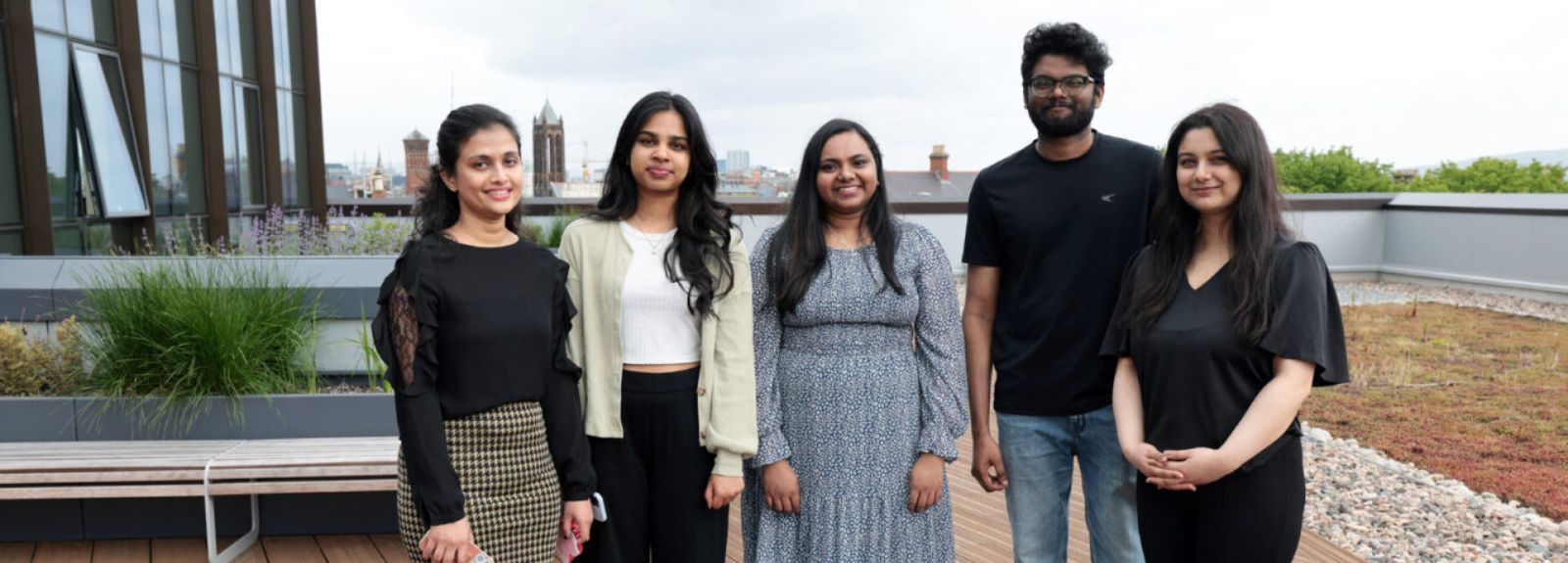 students standing on a roof terrace smiling to camera