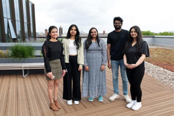 students standing on a roof terrace smiling to camera