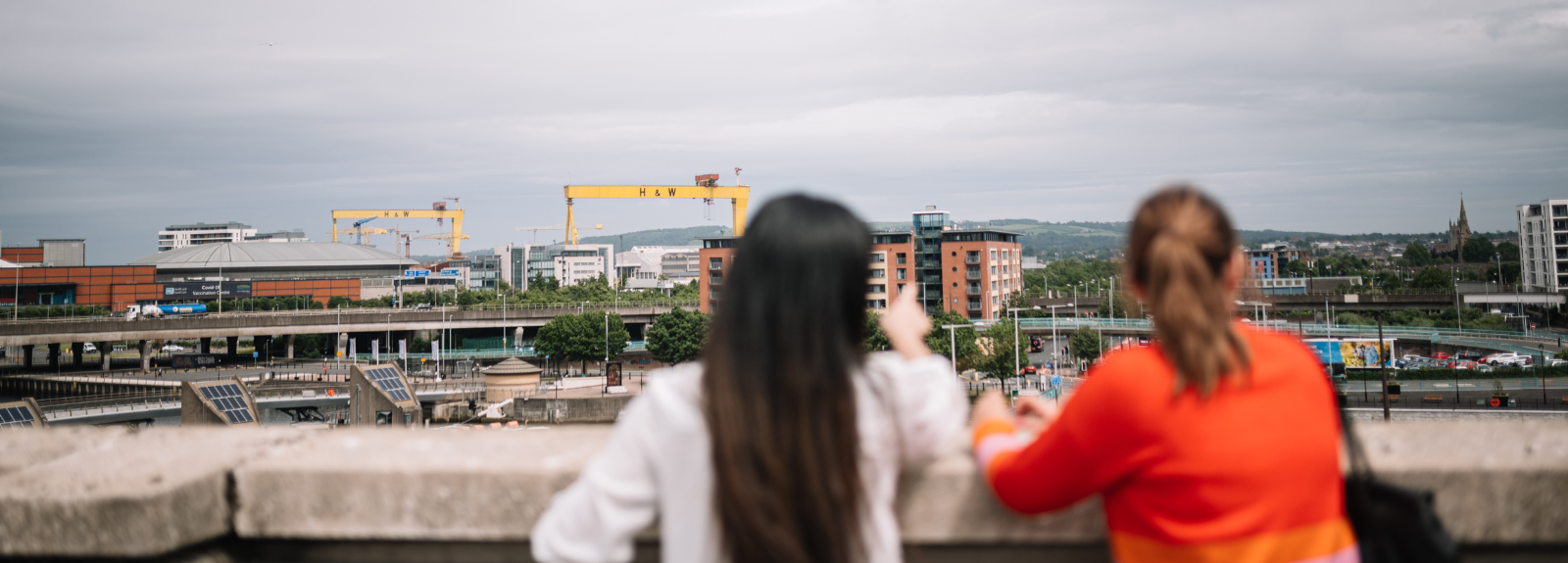 two students standing on a rooftop looking at a view of a city