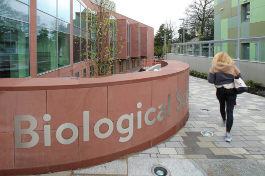 student walking towards Queen's biological sciences building