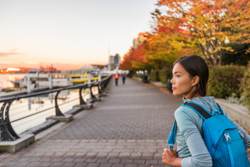 student walking through a park with trees over head