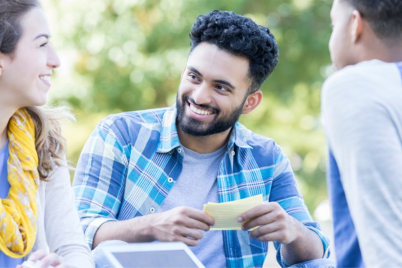 students sitting together outdoorsmwith study cards