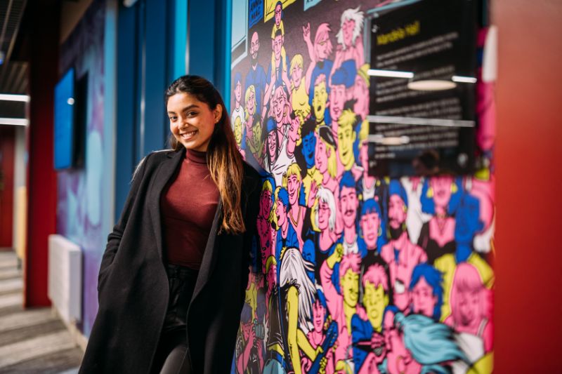 female student standing against wall artwork