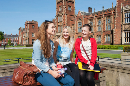 3 students chatting on a wall outside the front of the Lanyon Building