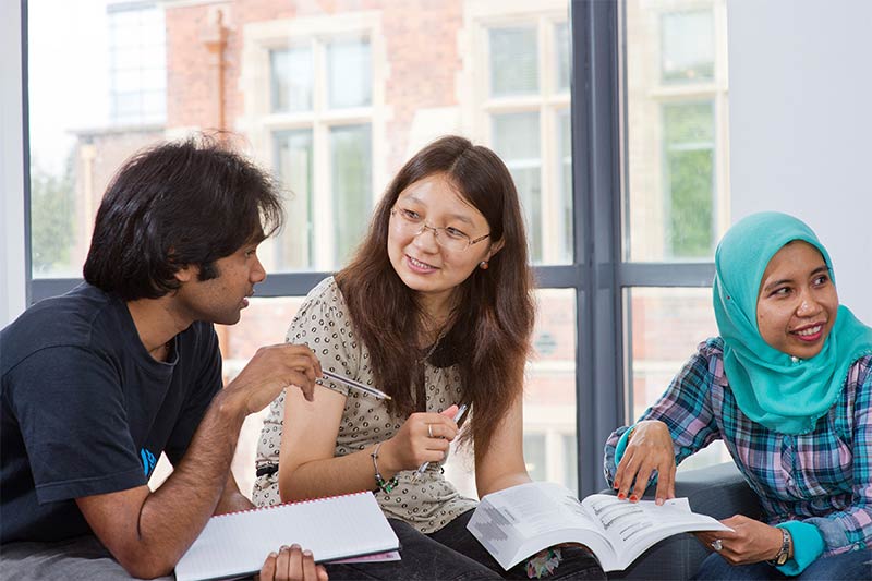 three international students discussing notes together