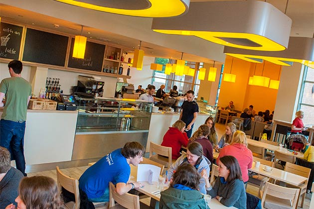 A wide angle view of Hope Café in the McClay library with numerous groups of students chatting and working