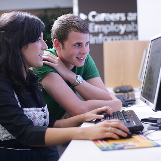 two students working together on a computer in the McClay Library
