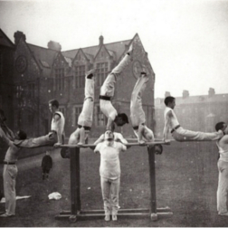 10 members of the Queen's gymnastic team (1900) performing a gymnastic routine in the grounds of Queen's University Belfast