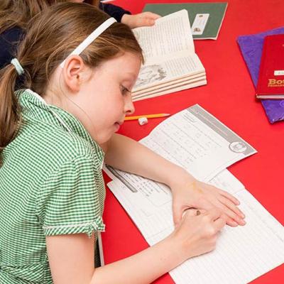 girl in school uniform doing her homework at the after school club