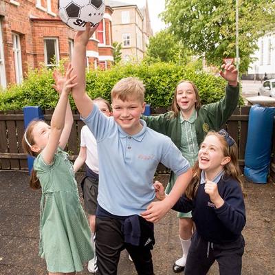 group of children playing outside at the after school club with one boy holding a football