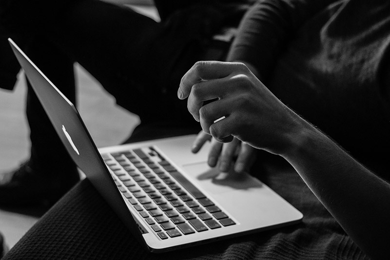 A black and white image of hands typing on a laptop