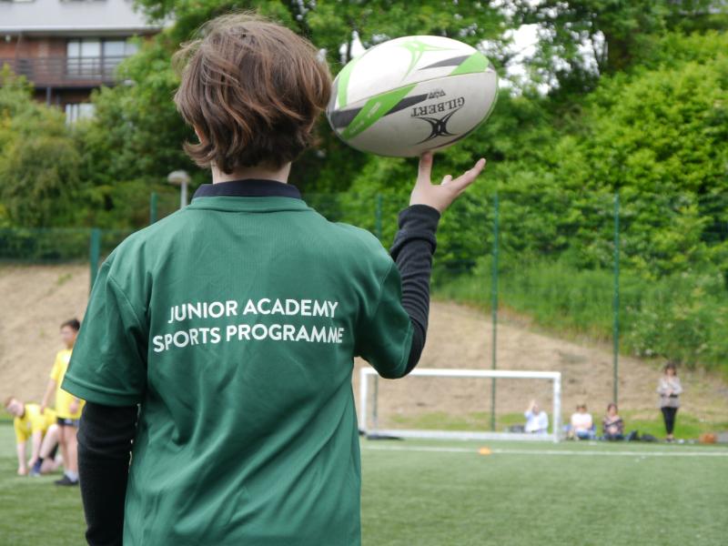 Y8 boy wearing JASP t shirt balancing a rugby ball on his thumb 