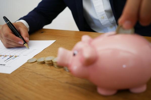 picture of a piggy bank and a person writing on a notepad 